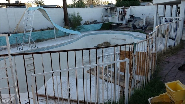 view of pool featuring a fenced in pool, a water slide, and fence