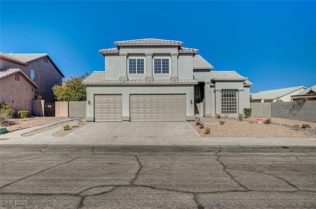 mediterranean / spanish home with stucco siding, driveway, a tile roof, fence, and an attached garage