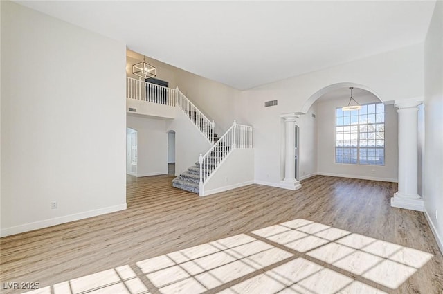 entryway featuring wood finished floors, baseboards, visible vents, ornate columns, and arched walkways