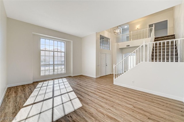 living room featuring a notable chandelier, stairway, baseboards, and wood finished floors