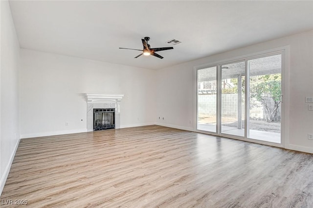 unfurnished living room featuring a ceiling fan, wood finished floors, visible vents, and a fireplace