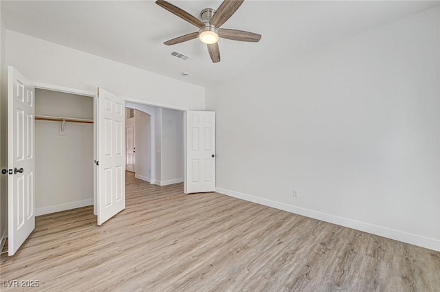 unfurnished bedroom featuring a ceiling fan, visible vents, baseboards, light wood-style floors, and a closet