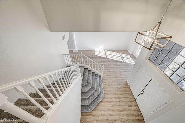 staircase featuring an inviting chandelier and wood finished floors