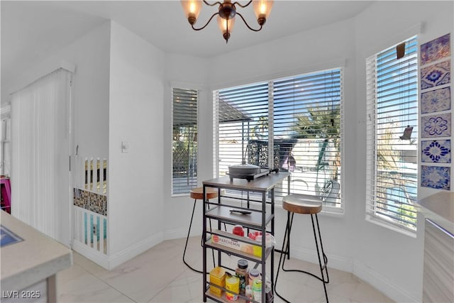 dining space featuring a healthy amount of sunlight, baseboards, and an inviting chandelier