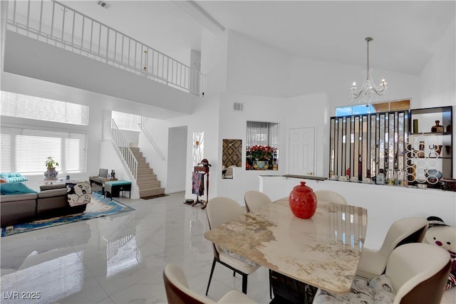 dining space featuring a high ceiling, marble finish floor, an inviting chandelier, and stairs