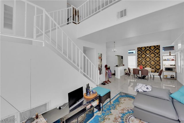 living area featuring visible vents, marble finish floor, a towering ceiling, and stairs