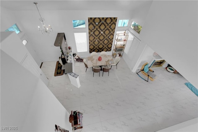 living area featuring a notable chandelier, a high ceiling, plenty of natural light, and marble finish floor