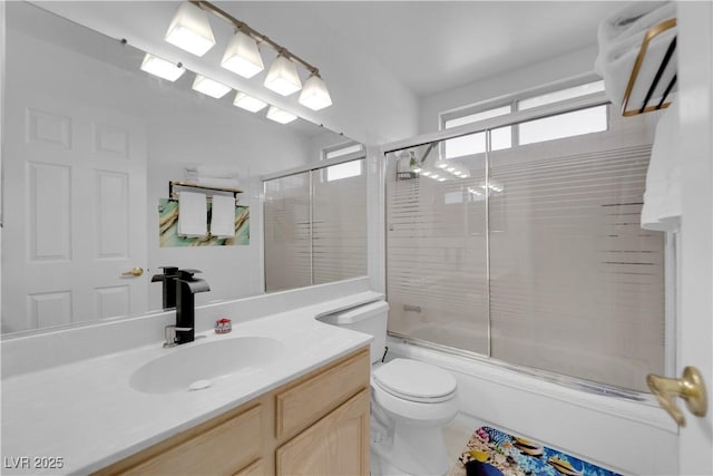 bathroom featuring enclosed tub / shower combo, toilet, and vanity