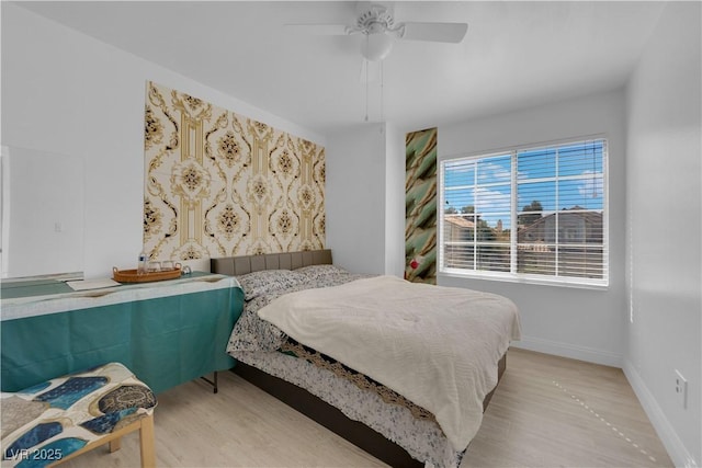 bedroom with light wood finished floors, a ceiling fan, and baseboards