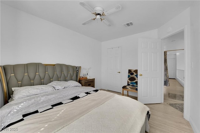 bedroom with light wood-style flooring, visible vents, and ceiling fan