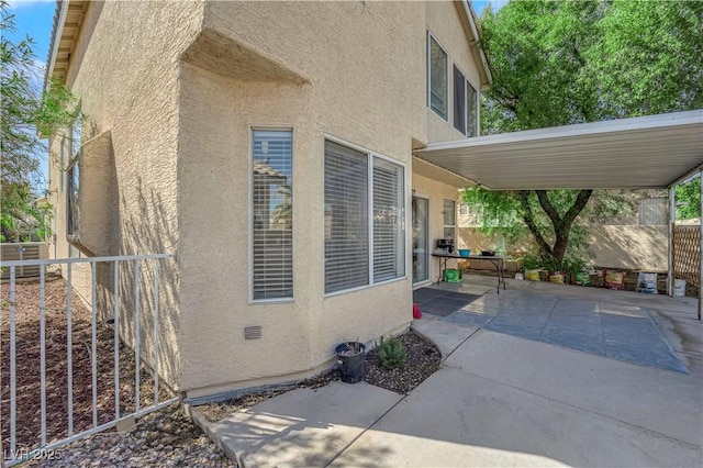 view of property exterior featuring a patio area, stucco siding, and fence