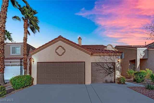 view of front facade featuring a tiled roof, a garage, driveway, and stucco siding