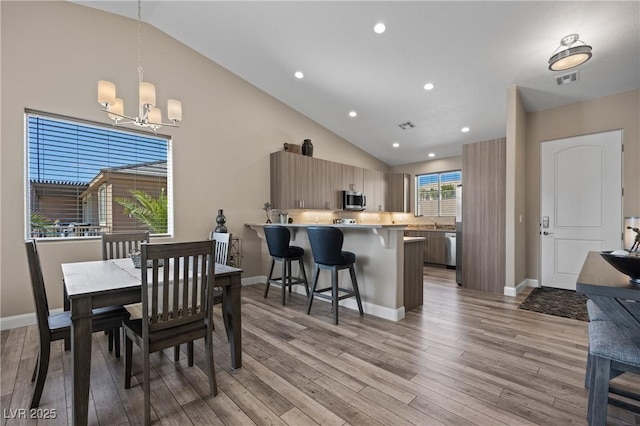 dining space featuring light wood-type flooring, baseboards, visible vents, and a chandelier