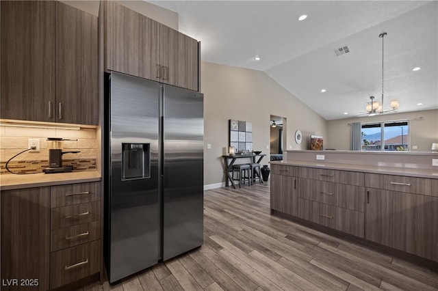 kitchen featuring modern cabinets, light countertops, stainless steel fridge with ice dispenser, and visible vents