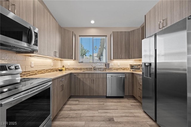 kitchen featuring modern cabinets, appliances with stainless steel finishes, light countertops, and a sink