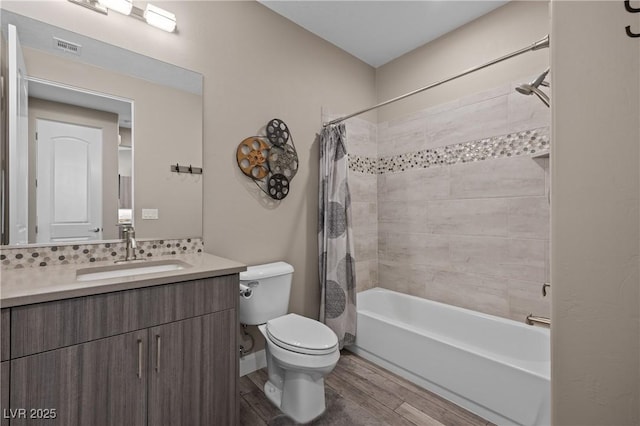 bathroom featuring toilet, backsplash, wood finished floors, shower / tub combo, and vanity