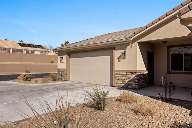 view of property exterior with driveway, an attached garage, stucco siding, stone siding, and a tile roof