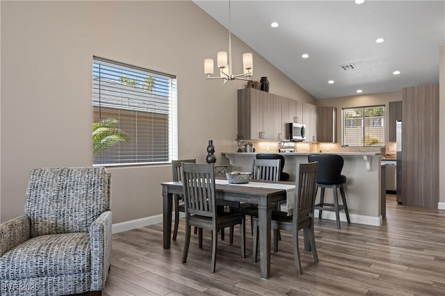 dining room with an inviting chandelier, baseboards, visible vents, and light wood-type flooring