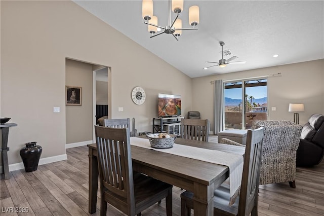 dining space with wood finished floors, visible vents, baseboards, vaulted ceiling, and ceiling fan with notable chandelier