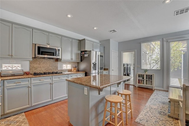 kitchen featuring washer and dryer, light wood finished floors, visible vents, and appliances with stainless steel finishes