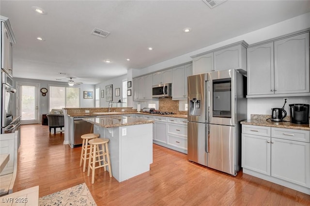 kitchen featuring light wood-type flooring, visible vents, a sink, stainless steel appliances, and a peninsula