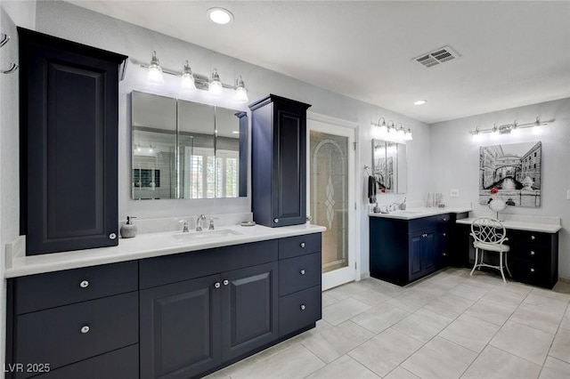 bathroom featuring visible vents, a stall shower, two vanities, and a sink