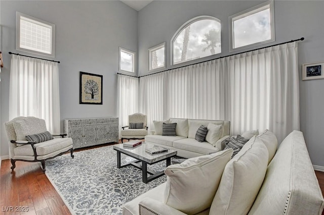 living area featuring baseboards, a high ceiling, and hardwood / wood-style floors