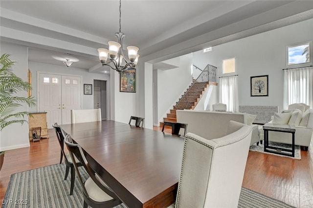 dining area with a notable chandelier, stairs, baseboards, and wood finished floors