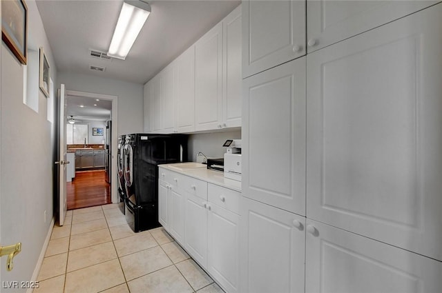 kitchen with visible vents, washing machine and dryer, light countertops, light tile patterned floors, and white cabinetry