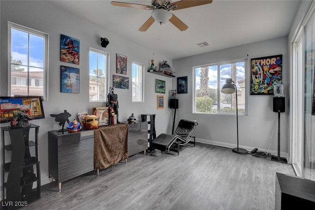 interior space with visible vents, baseboards, a ceiling fan, and wood finished floors