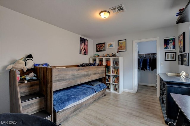 bedroom featuring light wood-type flooring, visible vents, a closet, baseboards, and a spacious closet