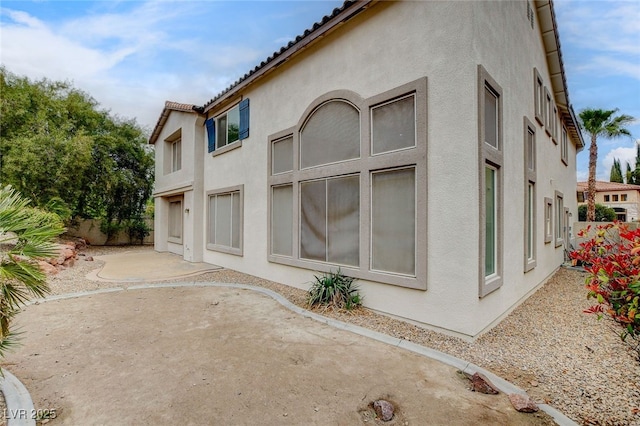 back of property with a tiled roof, a patio area, fence, and stucco siding