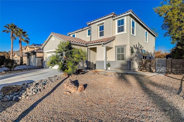 mediterranean / spanish house featuring fence, a tile roof, stucco siding, a garage, and driveway