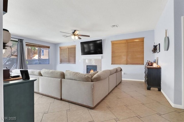 living room featuring visible vents, baseboards, a glass covered fireplace, and a ceiling fan