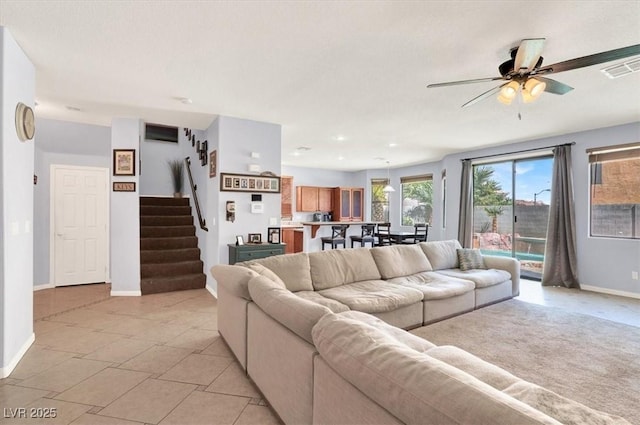 living room featuring stairway, visible vents, baseboards, and ceiling fan