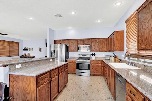 kitchen featuring a sink, a kitchen island, recessed lighting, appliances with stainless steel finishes, and brown cabinetry