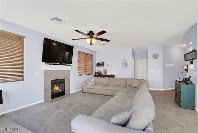 tiled living room featuring visible vents, baseboards, a ceiling fan, and a tile fireplace