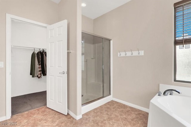 bathroom with tile patterned flooring, a stall shower, a bath, and baseboards