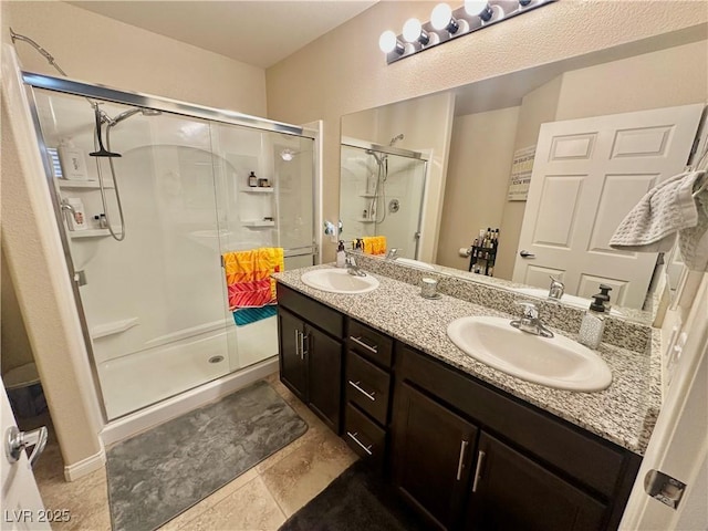 bathroom featuring a shower stall, double vanity, and a sink