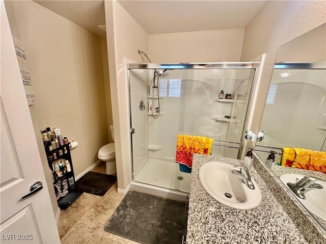 full bath with vanity, toilet, baseboards, and a stall shower