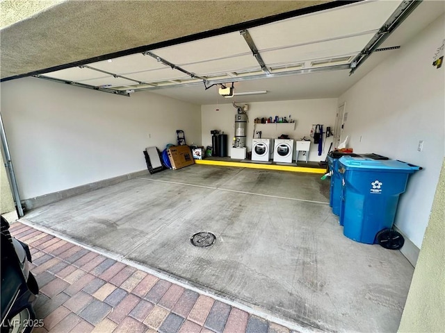 garage featuring washing machine and clothes dryer, secured water heater, and a garage door opener