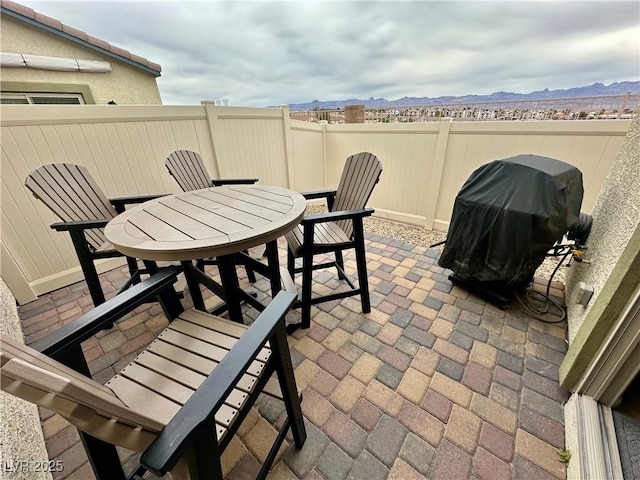 view of patio / terrace featuring outdoor dining space, area for grilling, fence, and a mountain view