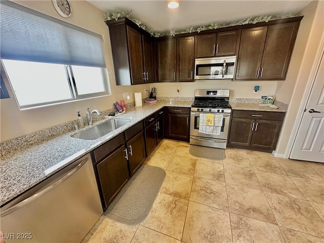 kitchen with a sink, stainless steel appliances, dark brown cabinetry, and light tile patterned floors