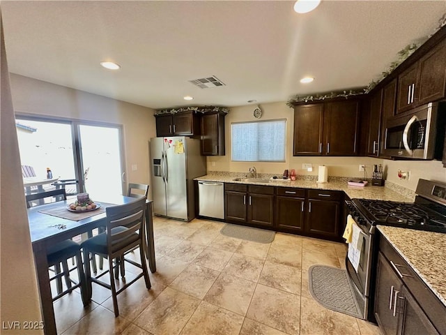 kitchen with a sink, dark brown cabinetry, visible vents, and stainless steel appliances