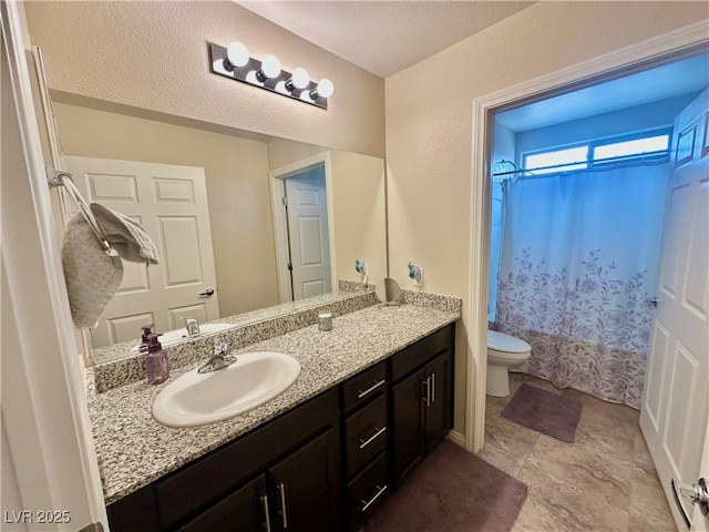 full bathroom with a textured ceiling, toilet, and vanity