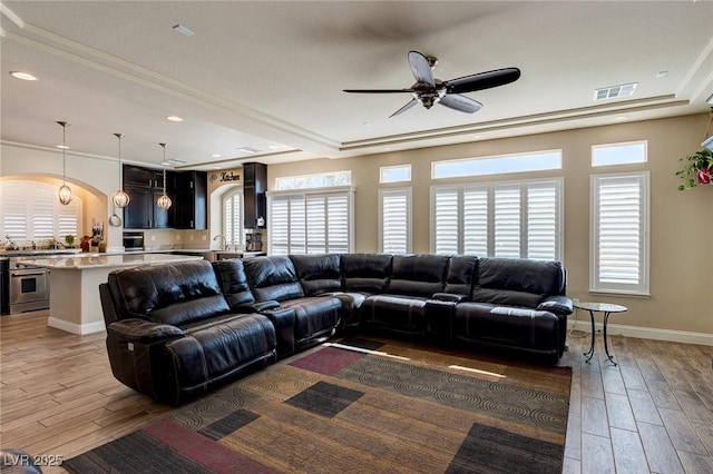 living room with arched walkways, wood finished floors, visible vents, and ceiling fan