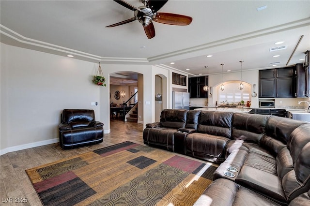 living room featuring wood finished floors, a ceiling fan, baseboards, recessed lighting, and arched walkways