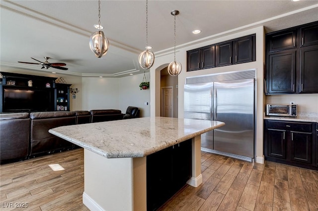 kitchen featuring light stone counters, a ceiling fan, light wood-style floors, and stainless steel built in fridge