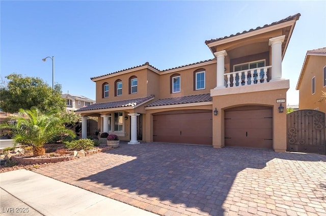 mediterranean / spanish-style house with stucco siding, decorative driveway, an attached garage, and a gate