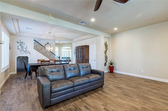 living room with visible vents, arched walkways, wood finished floors, and ceiling fan with notable chandelier